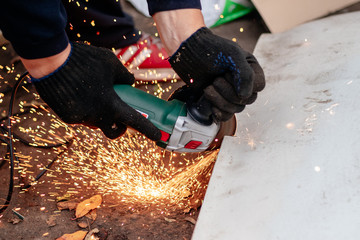 A man works with an angle grinder. Cuts metal.