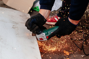 A man works with an angle grinder. Cuts metal.