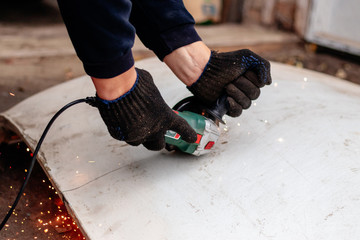 A man works with an angle grinder. Cuts metal.