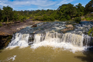 Drone shot, top view, of a stream with some small waterfalls, on a stony surface, surrounded by trees, on a sunny day,Tadton Waterfall,Ubonratchathani Porvince, North Eastern of Thailand,ASIA.