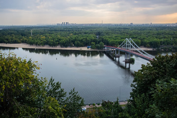 Tour of Kiev in the center of Europe. View of the Dnieper, Trukhanov island and a foot bridge. Park fountain and sunset on the horizon..