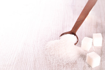 White cane sugar on a light wooden background