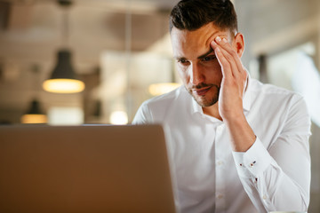 Close up of tired businessman working on laptop in office