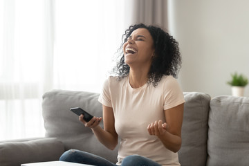 Obraz premium Overjoyed black woman laughing getting funny message on smartphone