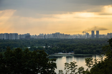 Fototapeta premium Tour of Kiev in the center of Europe. View of the Dnieper, Trukhanov island and a foot bridge. Park fountain and sunset on the horizon..