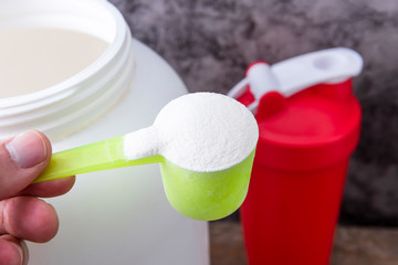 Sport nutrition supplement containers with shaker. Close up of protein powder and scoop