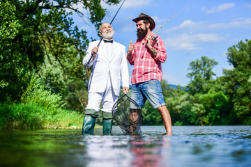Friends fishing. Elegant bearded man and brutal hipster fishing. Perfect weekend. Family day. Summer vacation. Fishing as holiday. Hobby and recreation. Fisherman in formal suit. Successful catch