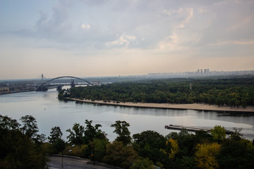 Tour of Kiev in the center of Europe. View of the Dnieper, Trukhanov island and a foot bridge. Park fountain and sunset on the horizon..