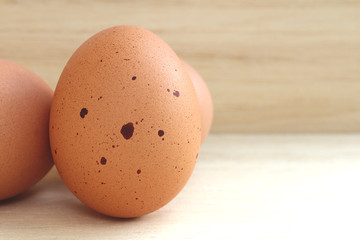The skin of the egg has strange black spots. On a light brown wooden floor