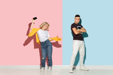 Fototapeta premium Young emotional man and woman in bright casual clothes posing on pink and blue background. Concept of human emotions, facial expession, relations, ad. Man's sad, woman's astonished, crazy happy.