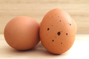The skin of the egg has strange black spots. On a light brown wooden floor