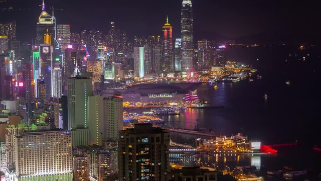 Timelapse pictorial Wan Chai district in Hong Kong with illuminated highrise buildings and skyscrapers by large harbour at night zoom out