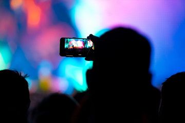 Hands with a smartphone records live music festival