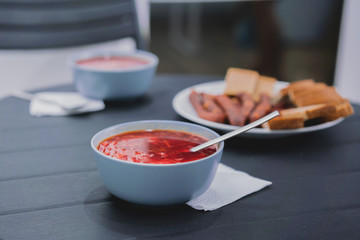 A plate of red soup Borshch on the black table. Soup 