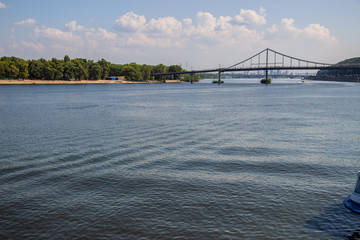 Naklejka premium Tour of Kiev in the center of Europe. View of the Dnieper, Trukhanov island and a foot bridge. Park fountain and sunset on the horizon..