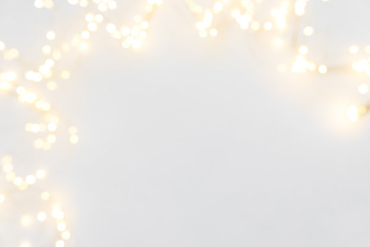 Border of defocused Christmas lights on white wooden background. Christmas and New Year holidays celebration concept
