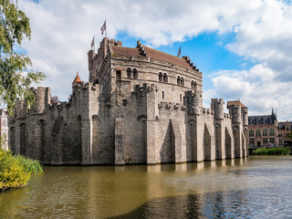 Fototapeta na wymiar Castle of the Counts next to river Lys in Ghent, Belgium. Famous fortress in Gent old town. Beautiful architecture and landmarks of the medieval city on a sunny day.