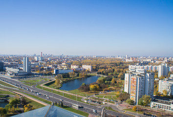 Fototapeta na wymiar City architectural landscape Minsk. Office buildings of the road and parks. View from the roof with blue sky.