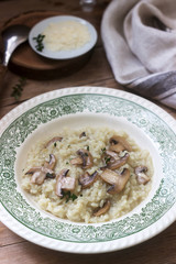 Traditional italian dish risotto with champignons in a light plate on a wooden table. Rustic style.