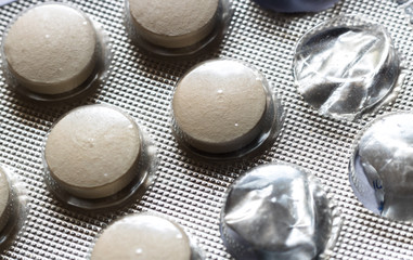 Yellowish medicine tablets packed in silver blister with some containers empty. Close up medicine...