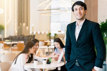 portrait of smart asian engineeer hand hold laptop with background of meeting group in modern design office