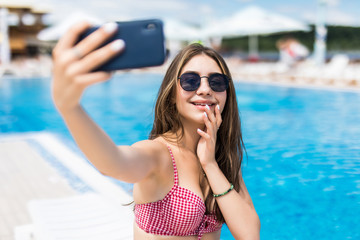 Portrait of beautiful girl taking selfie at the swimming pool.