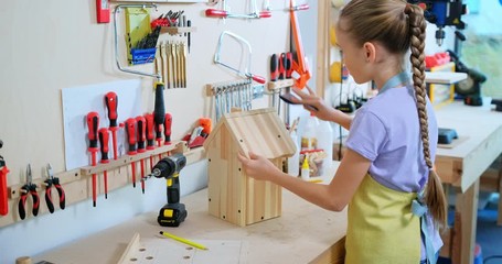 Preteen girl making the wooden nesting box in the workshop