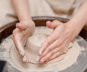 Female hands working on pottery wheel making ceramic bowl
