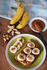 Healthy snack or breakfast, bread toast with peanut butter and banana, seasoned with cinnamom.