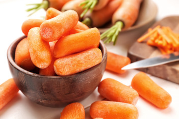 Bowl with fresh carrots on table