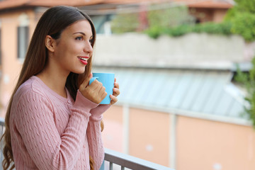Portrait of beautiful girl enjoying hot drink in the morning at home before going to work outdoors.
