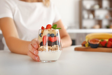 Woman with tasty fruit salad in glass on table