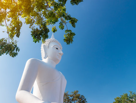 White Buddha statue used as amulets of Buddhism religion. Buddha statue sitting in public temple with blue sky background.