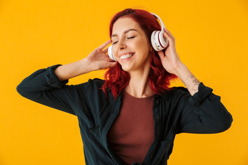 Image of cute smiling woman listening music with headphones