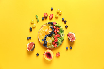 Plate with tasty fruit salad on color background