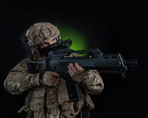 a male soldier in military clothes with a weapon on a dark background