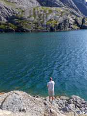 landscape with rocks, clear and blue fjord water, mountains in the background