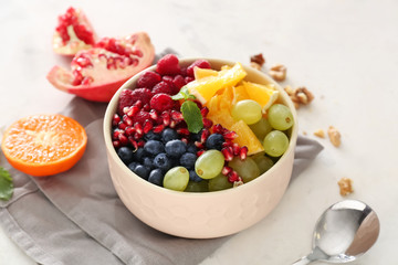 Bowl with tasty fruit salad on light background