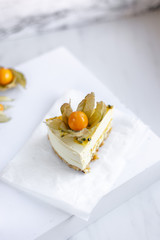 Passionfruit vegan cheesecake with Physalis on marble background with copy space