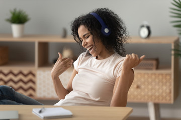 Fototapeta na wymiar Excited black girl have fun listening to music in headphones