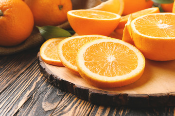 Board with orange slices on wooden table