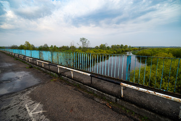 Fototapeta premium Old bridge, river and trees on calm day. Natural landscape