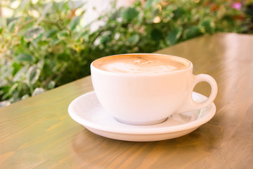 white cup with coffee on the table, in the morning, in a cafe on a bright veranda, close-up, selective focus