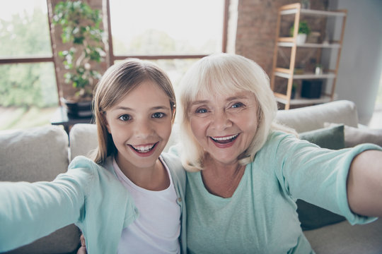 Closeup photo of two people white haired grandma small granddaughter making selfies video call skype spending summer weekend together house indoors