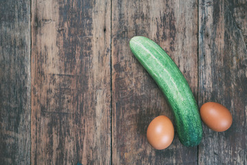 The cucumber that made the concept of the male penis rests on a dark brown wood floor.