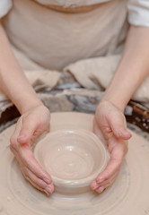Female hands working on pottery wheel making ceramic bowl