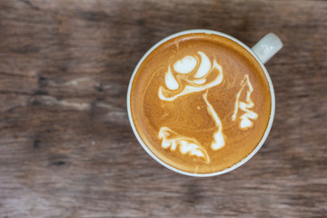 Latte art coffee with bean art texture on wooden table