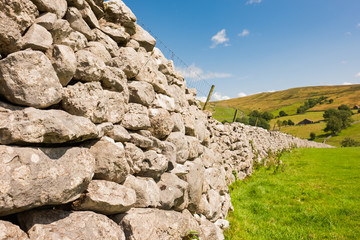Detailed, scenic vew of an old rock wall seen in the picturesque Yorkshire Dales. Stretching to the distance it is used as grazing meadows for ship and cattle.