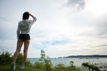 girl stands on a hill with her back and looks at the sea   