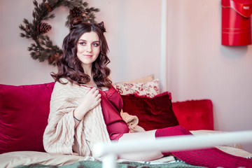 Beautiful pregnant woman in a burgundy chemise and leggings poses on the bed in a New Year s...
